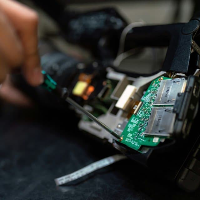 Technician repairing a circuit board with a screwdriver