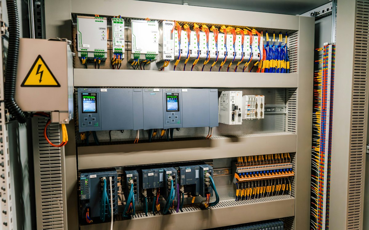 Open control cabinet with PLC modules and wiring